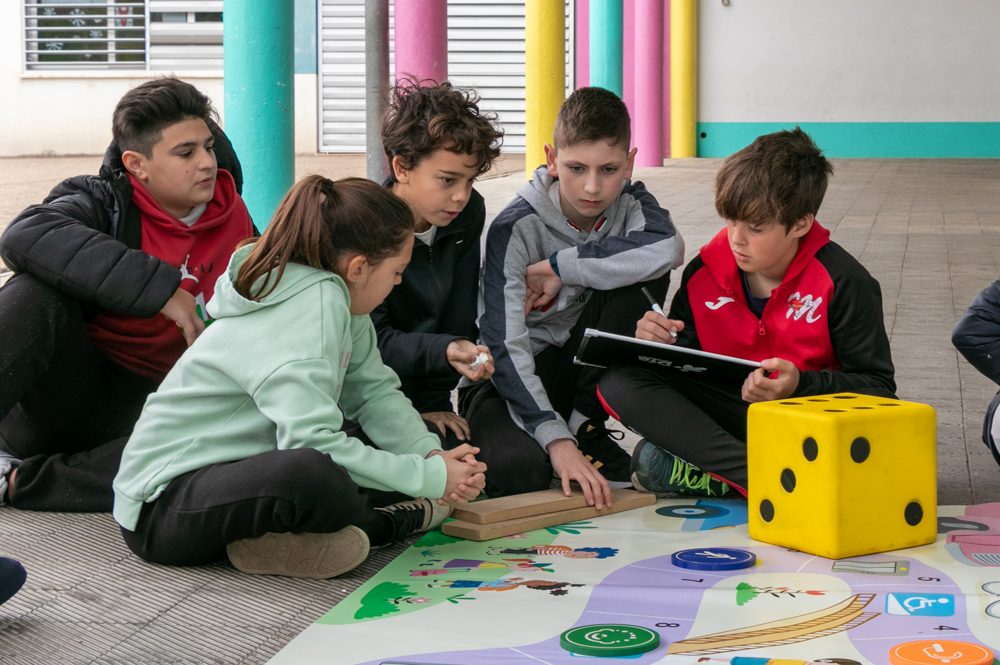 Alumnos y alumnas jugando al juego de lona en el aula y dibujando en una pizarra magnética